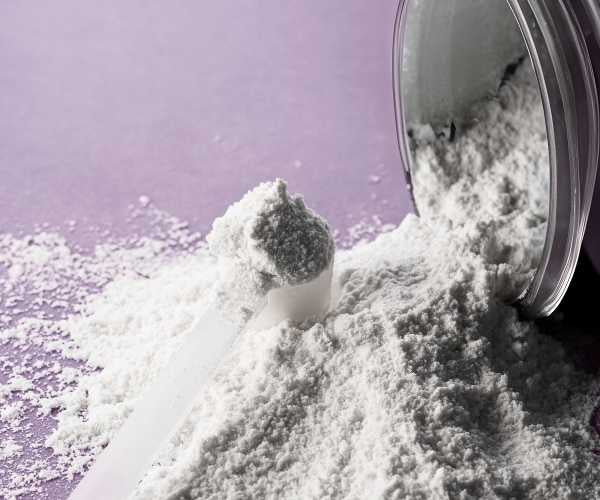 White powder being poured from a container onto a purple surface